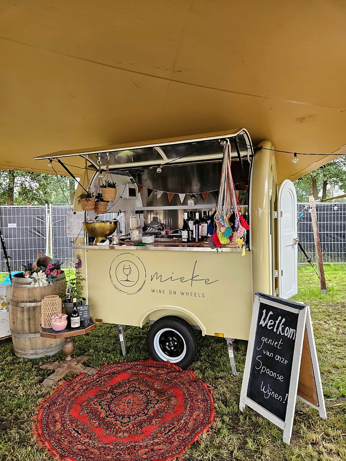 De wijnkar van Mieke Wine on Wheels onder de tent, met een wijnvat en een krijtbord